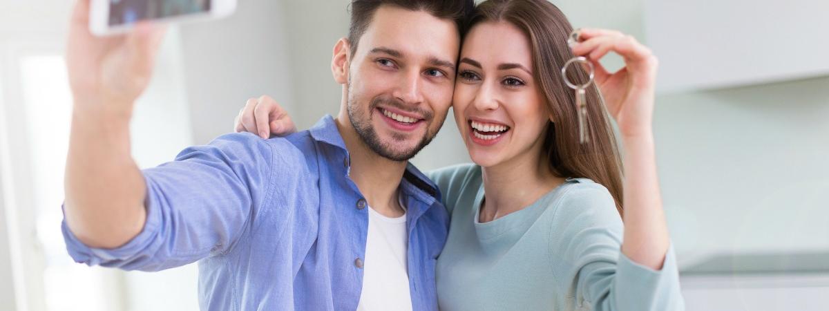 picture of new home buyers with a photo of their new house
